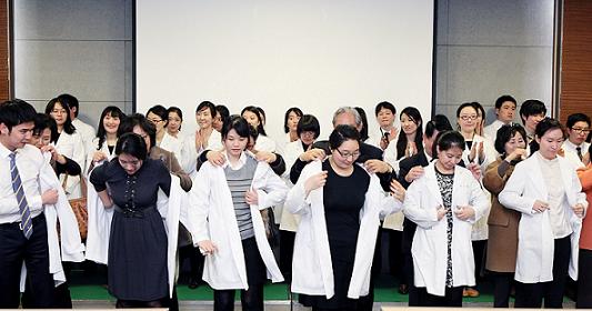 이대목동병원 대회의실에서 개최된 2012 신입 인턴 가족 초청 행사에서 가족들이 직접 인턴들에게 의사 가운을 입혀 주고 있다.